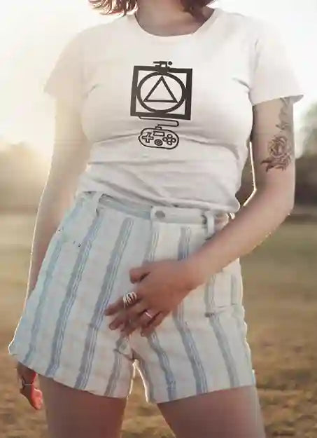 Woman wearing a white t-shirt with a black graphic design featuring a triangle inside a circle, which is inside a square, with a game controller below. She is also wearing striped shorts. | Satire Clothes