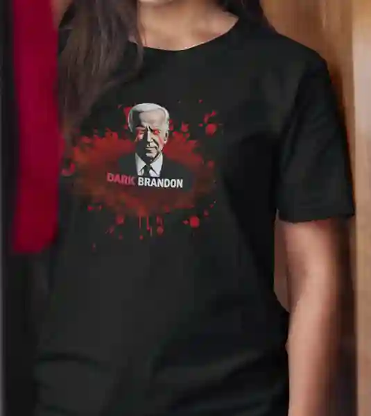 A woman wearing a black t-shirt featuring a graphic of a man with white hair in a suit, surrounded by red splatter effects, with the text 'DARK BRANDON' in bold white and red letters below the image | Satire Clothes