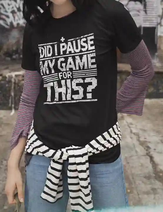 A woman wearing a black Satire t-shirt with white text reading "DID I PAUSE MY GAME FOR THIS?" in a distressed font, expressing humorous frustration over game interruptions | Satire Clothes