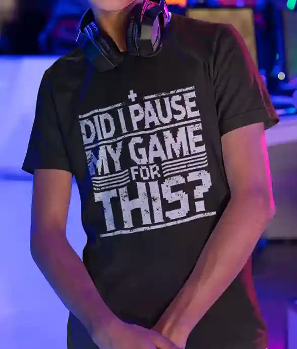 A man wearing a black Satire t-shirt with white text reading "DID I PAUSE MY GAME FOR THIS?" in a distressed font, expressing humorous frustration over game interruptions | Satire Clothes