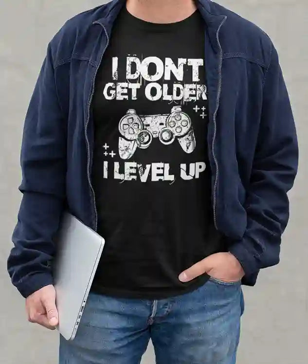 Man wearing a Black 'I Don't Get Older, I Level Up' T-Shirt with a graphic of a game controller and plus signs | Satire Clothes