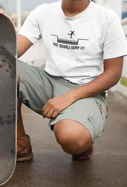 Man wearing a white t-shirt with a black graphic of a stick figure jumping over spikes and the text 'JUST DOUBLE JUMP IT!' below | Satire Clothes