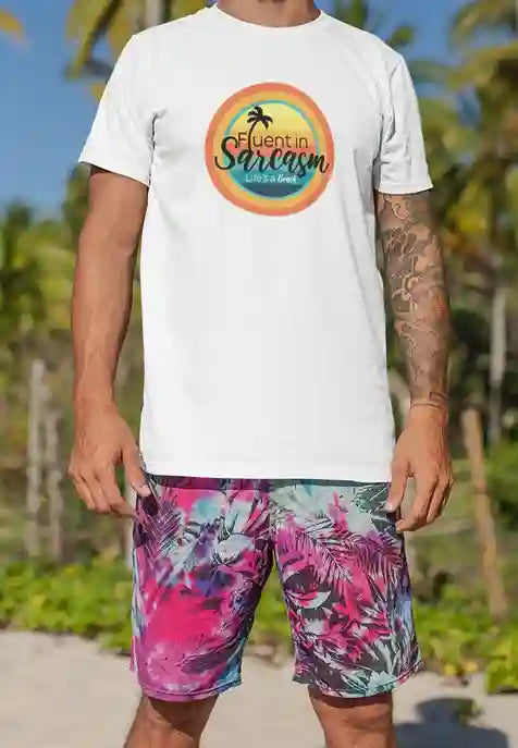 A man wearing a white t-shirt with a colorful circular design featuring a palm tree and the text "Fluent in Sarcasm Life's a Beach" in a playful font. | Satire Clothes