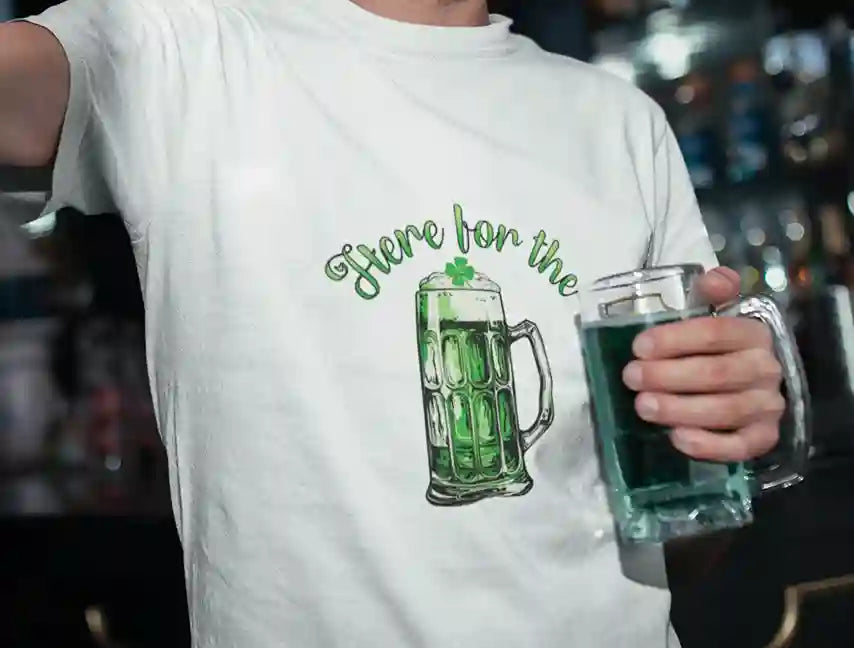 A man wearing a white T-shirt with a graphic of a green beer mug and the text "Here for the Beer" in green above it. | Satire Clothes