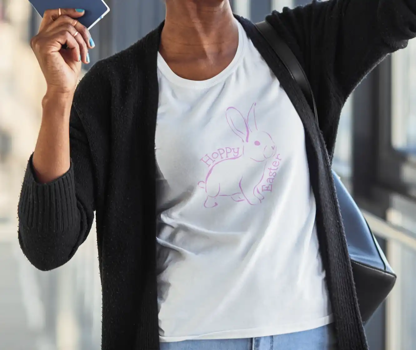 A woman wearing a white t-shirt with a playful pink outline of a bunny, surrounded by the words 'Hoppy Easter' in a whimsical font. | Satire Clothes