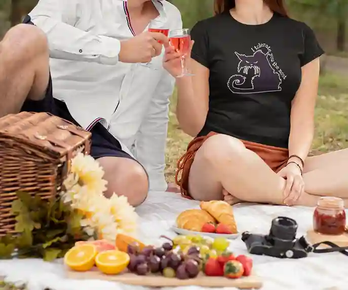 A woman wearing a black T-shirt with a white outline of an angry cat and the text "I tolerate you the most" printed on it | Satire Clothes