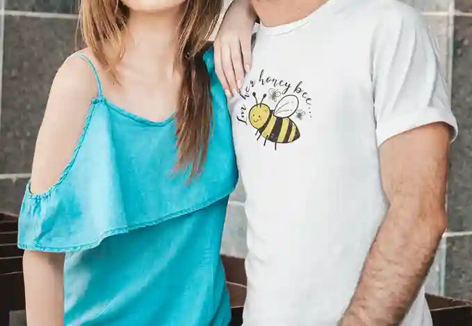 Man wearing white T-shirt featuring a playful design with a cartoon bee and the text 'I'm her honey bee' in black | Satire Clothes