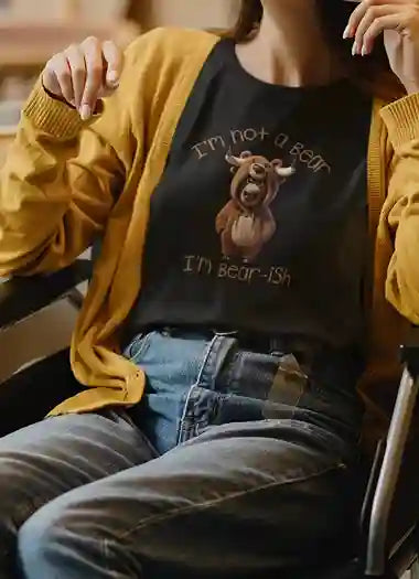 A woman wearing a black T-shirt with the design of a bull wearing a bear costume. Above the bull, text reads "I'm not a bear" and below, "I'm bear-ish" in brown font. | Satire Clothes