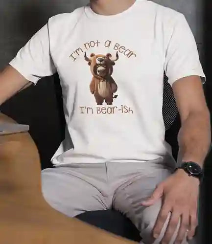 A man wearing a white T-shirt with the design of a bull wearing a bear costume. Above the bull, text reads "I'm not a bear" and below, "I'm bear-ish" in brown font. | Satire Clothes