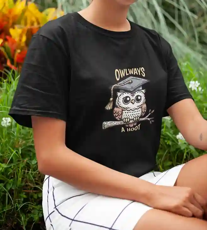 A woman wearing a black t-shirt featuring a cute owl with a graduation cap, perched on a branch, with the text "OWLWAYS" above and "A Hoot" below | Satire Clothes