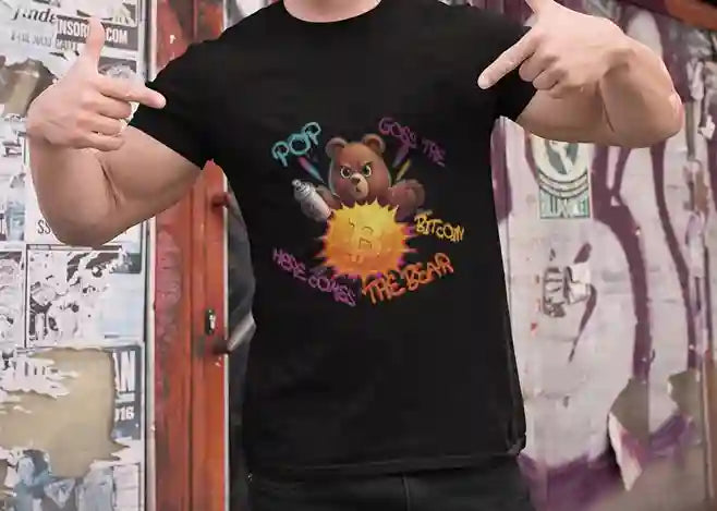 Man wearing black t-shirt with a humorous design featuring a bear holding a spray can, popping a Bitcoin symbol. Surrounding the bear, colorful graffiti text reads "POP! Goes the Bitcoin, Here Comes The Bear" | Satire Clothes