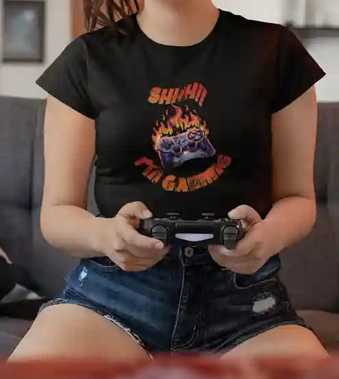 Woman wearing a black T-shirt with a graphic of a flaming game controller and the text "SHH!! I'M GAMING" in bold, fiery letters | Satire Clothes