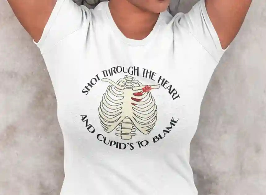 A woman wearing a white T-Shirt with a white skeleton ribcage design and the text 'Shot Through The Heart And Cupid's To Blame' encircling it | Satire Clothes