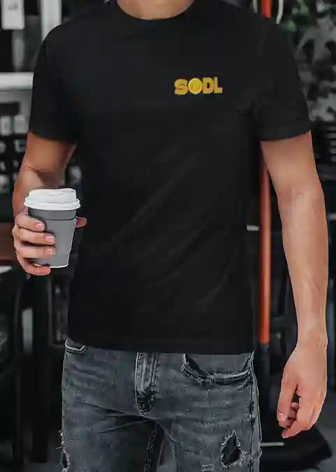 A man wearing a black t-shirt with 'SODL' printed in bold, gradient yellow-orange letters on the left chest | Satire Clothes