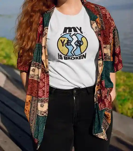 A woman wearing a white 'My Yes Is Broken' T-Shirt featuring a cracked 'YES' design in yellow and blue, with bold text above and below | Satire Clothes